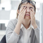 A woman at her computer rubbing her eyes