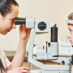 A young boy getting a slit lamp eye examination from an eye doctor