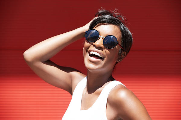 Happy woman wearing sunglasses in front of red wall